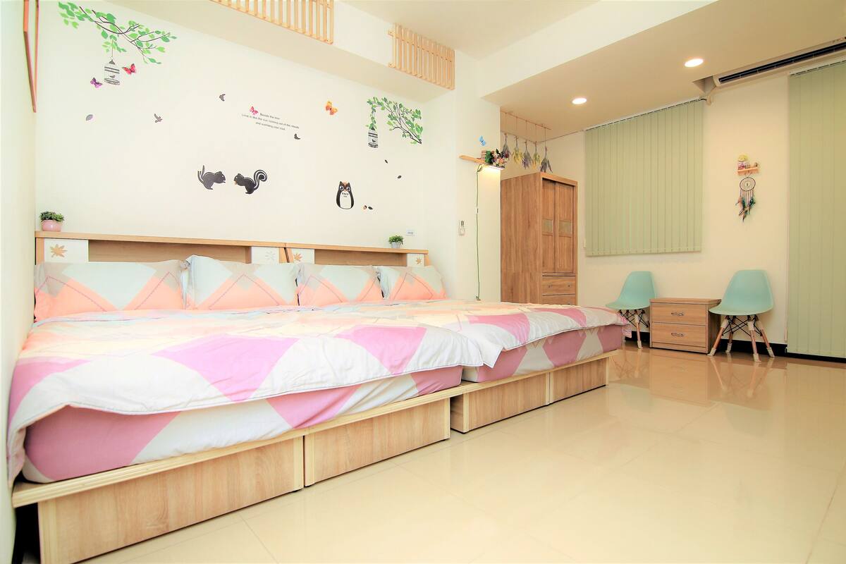 A bedroom with a large bed, a wardrobe, a desk, and a chair.