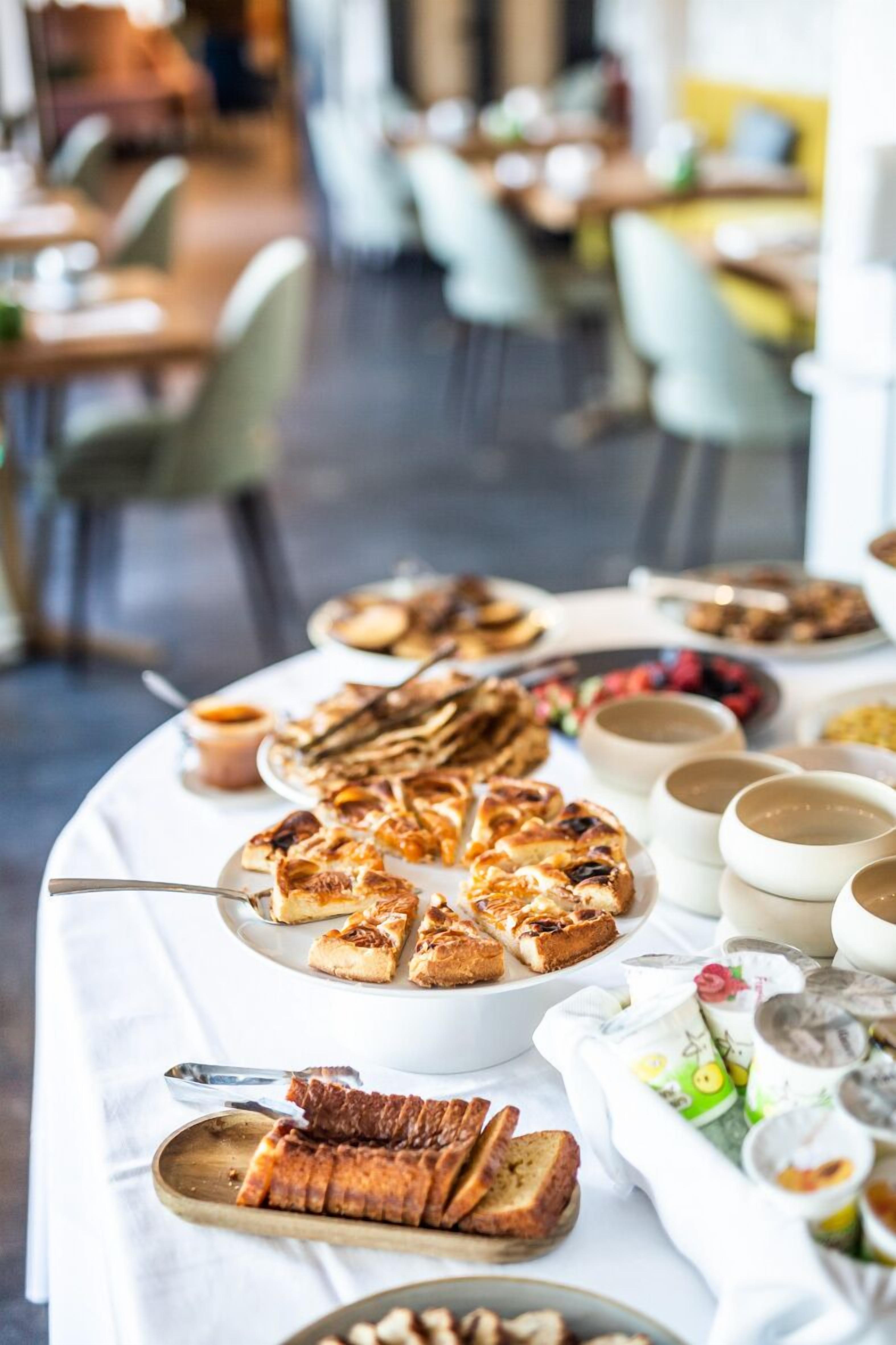 A buffet table with various dishes, including a large pie, bread, and small bowls of food.