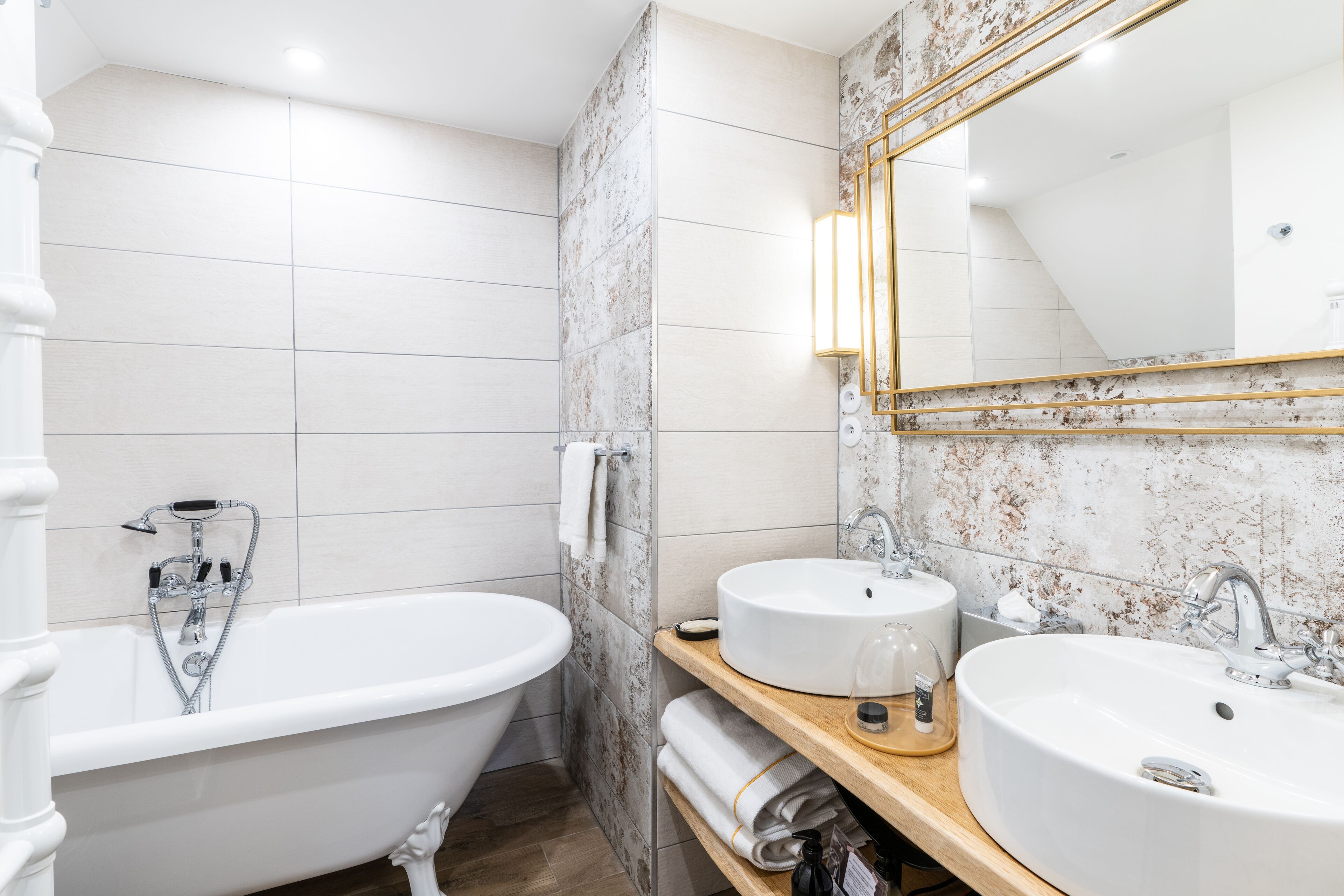 Un baño moderno con una bañera independiente, dos lavamanos y un espejo grande.
