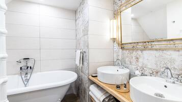 Un baño moderno con una bañera independiente, dos lavamanos y un espejo grande.