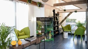 A modern lobby with green chairs, a large poster, and a staircase.