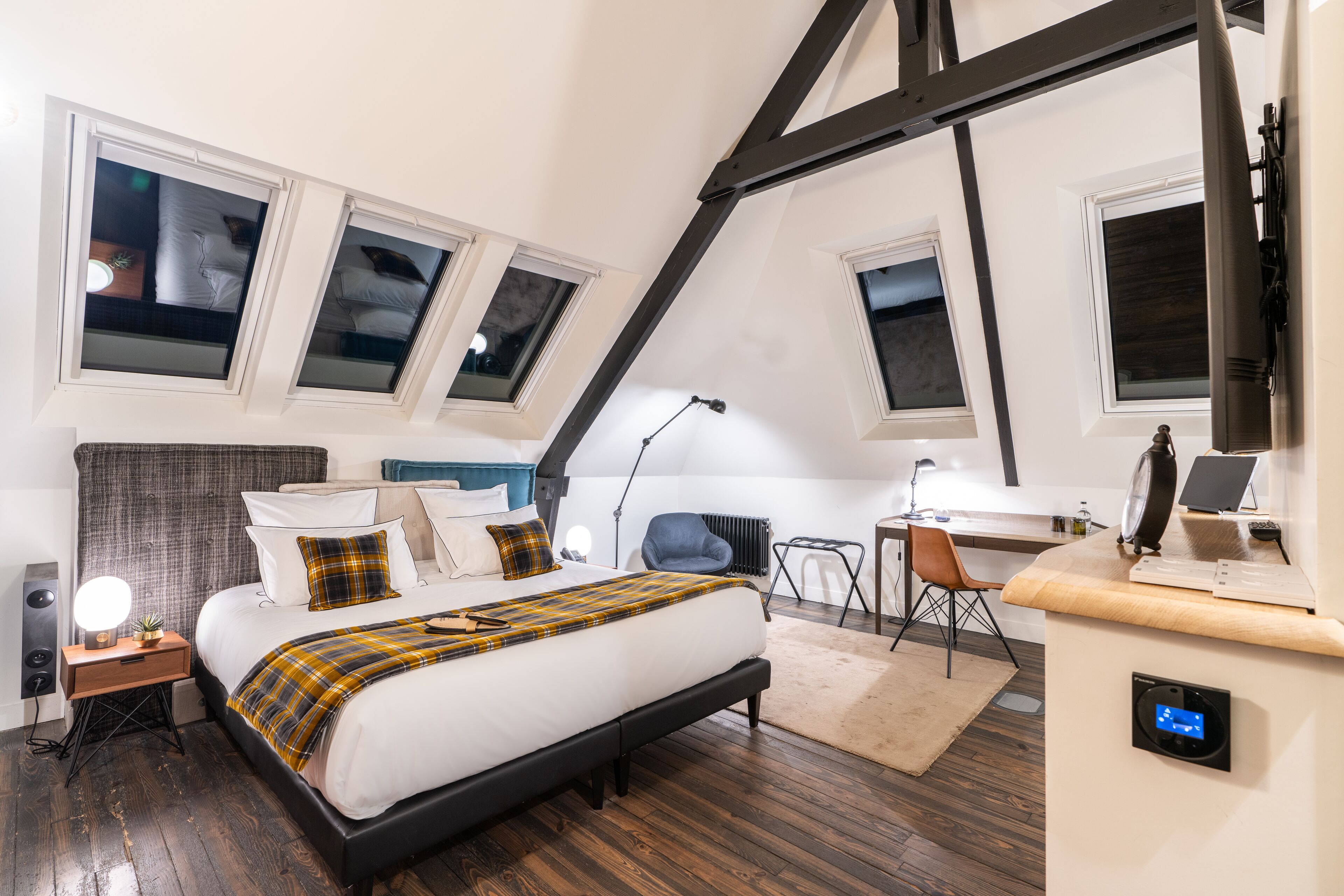 Een slaapkamer met een bed, bureau, stoel en een kleine tafel met een lamp.