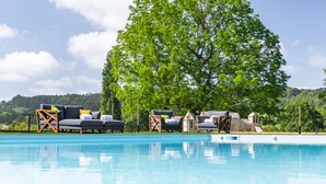 A poolside area with lounge chairs and a large tree.