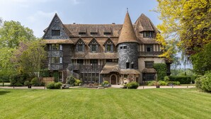 A large, historic building with multiple towers and a well-maintained lawn.