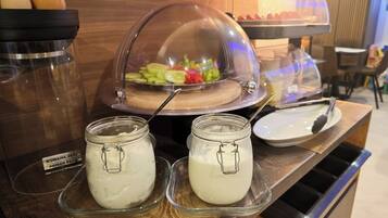 En buffetopsætning med en overdækket salat, to krukker med hvid smørecreme og en skål æg.