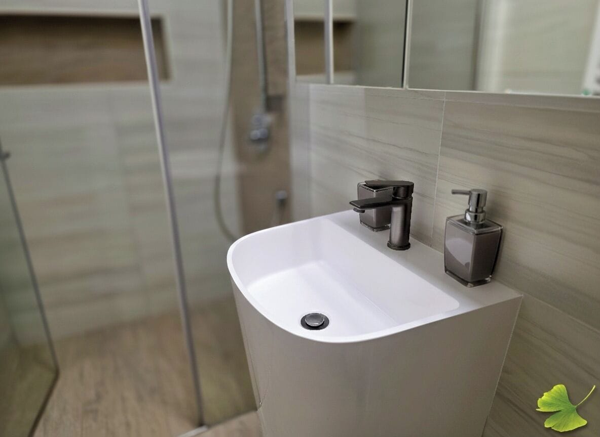 Uma casa de banho moderna com uma pia branca, uma torneira preta e um dispensador de sabonete.