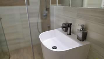 Uma casa de banho moderna com uma pia branca, uma torneira preta e um dispensador de sabonete.