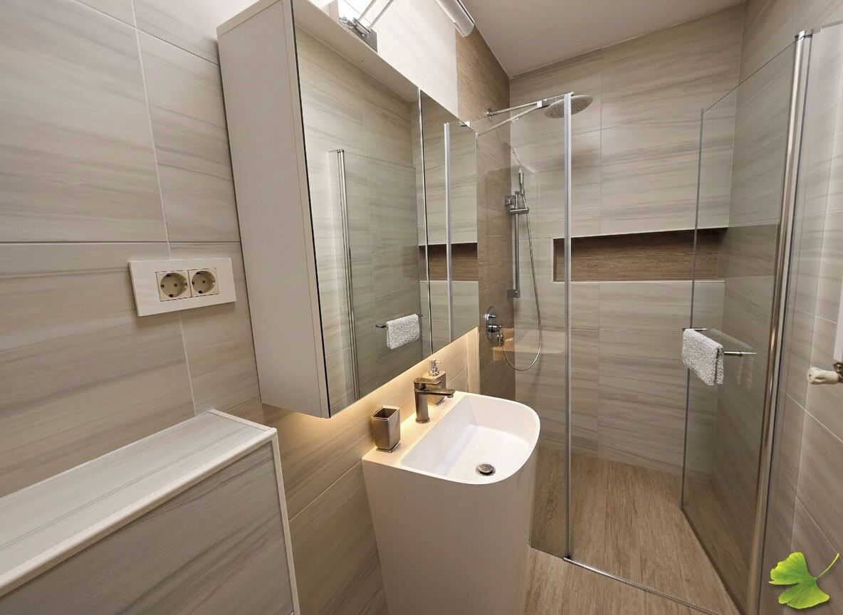 A modern bathroom with a glass-enclosed shower, a white sink, and a mirror above it.
