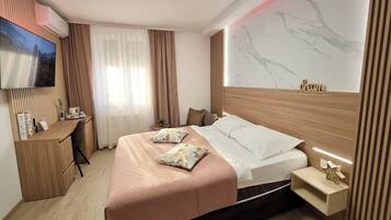 Una habitación de hotel moderna con cama, escritorio, televisión y pared de mármol.