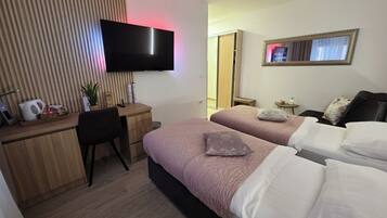 Habitación de hotel con dos camas, un escritorio, un televisor y un espejo.