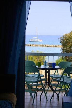 A balcony with a view of the sea, featuring a table with chairs and a sailboat in the distance. - Blue Coast (Limassol)