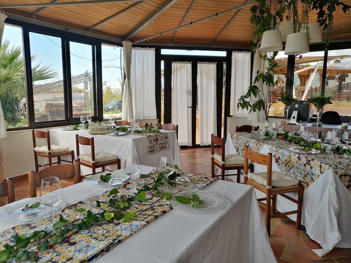 A restaurant with tables set for dining, featuring a covered outdoor area with large windows and curtains.