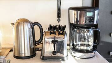 Una tetera Kenwood, un tostador y una cafetera sobre una mesa.