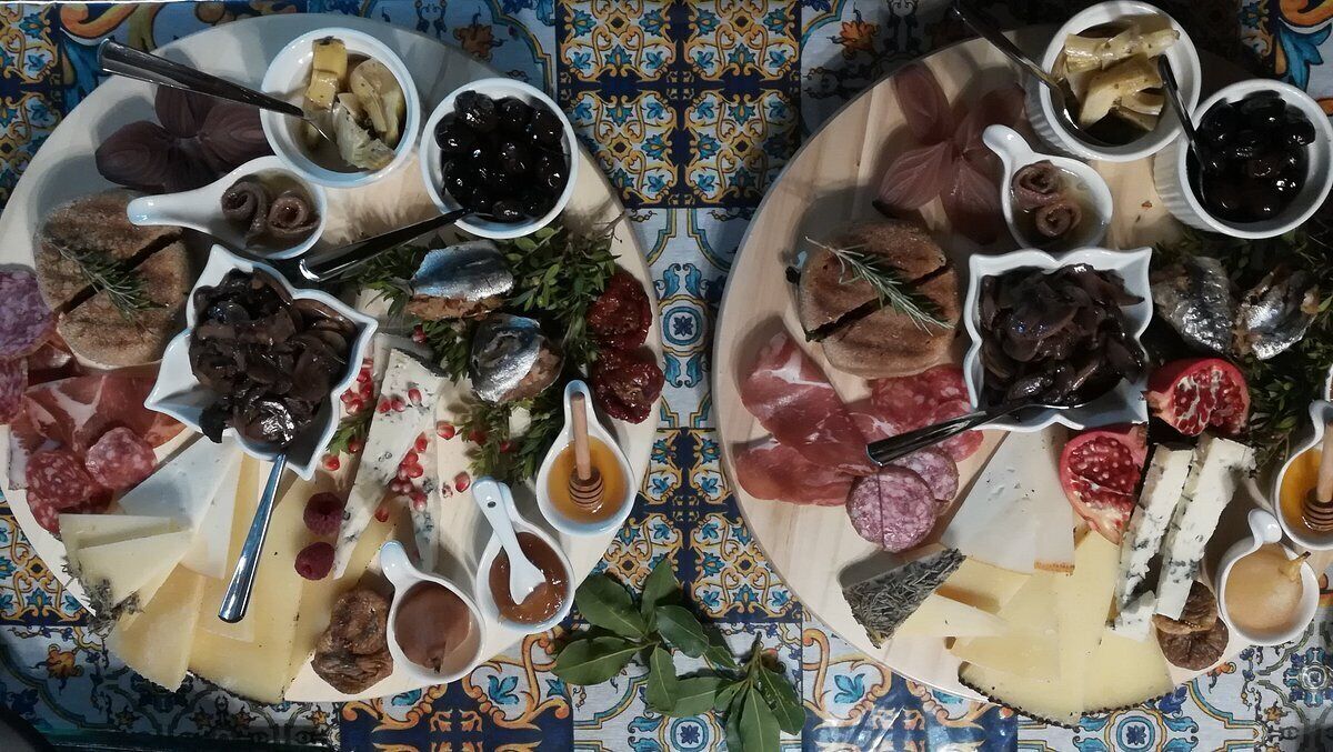 Una tabla de quesos y embutidos con diversas carnes, quesos y acompañamientos.