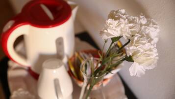 Een witte theepot en een witte kan op een tafel met een vaas witte bloemen.