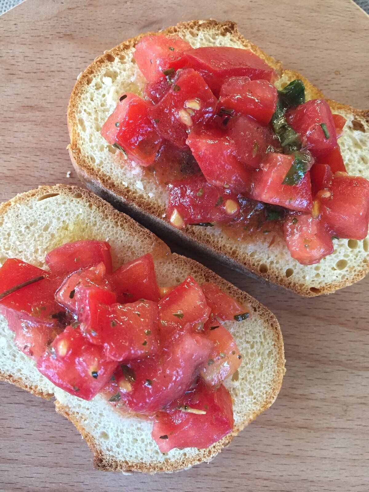 Two slices of bread topped with chopped tomatoes and herbs.