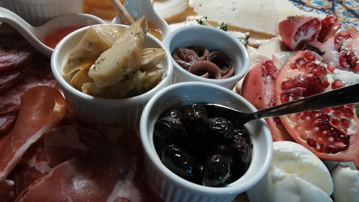Une planche de charcuterie comprenant différentes sortes de viandes, de fromages et de produits marinés.