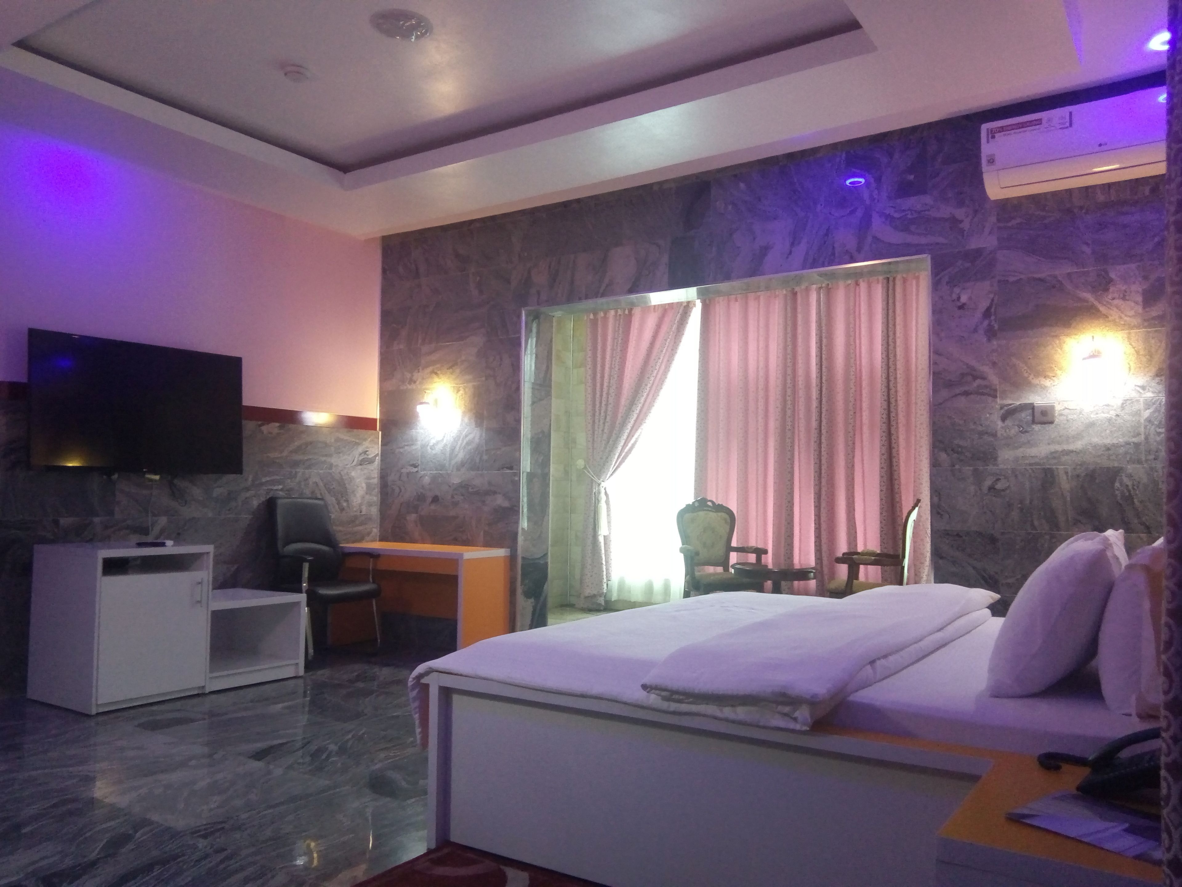 A hotel room with a bed, desk, chair, and a television.
