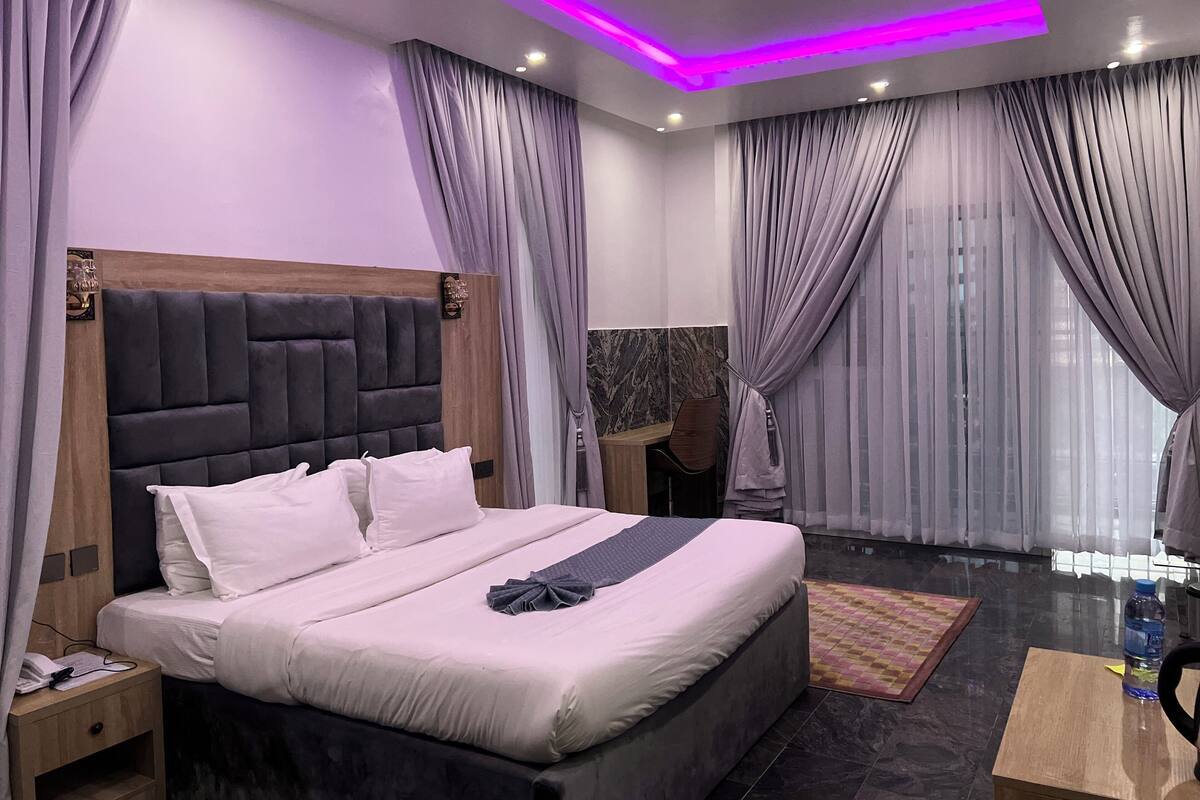 A modern bedroom with a large bed, a wooden headboard, and a nightstand.