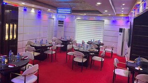 Une salle de conférence dotée de plusieurs tables et chaises, équipée de climatiseurs et de bouteilles d’eau.