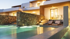 Een modern resort met een stenen muur, een overloopzwembad en een terras.