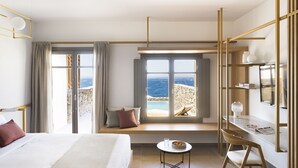 Een moderne hotelkamer met een groot bed, een bureau en uitzicht op zee.