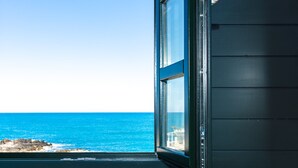 A room with a view of the ocean through an open window, a dark-colored wall, and a cushion with a geometric pattern. - Ink Hotels House of Europe (Rethymno)