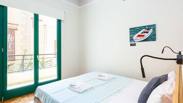 Hotelkamer met een bed, een raam met uitzicht op een gebouw en een schilderij van een boot aan de muur.