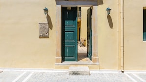 A doorway with a green door, a plaque, and a bench inside. - Ink Hotels House of Europe (Rethymno)