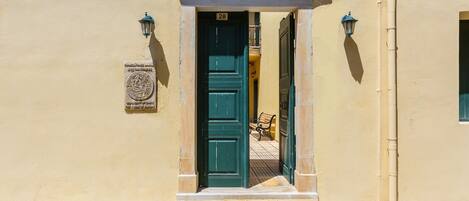A doorway with a green door, a plaque, and a bench inside.