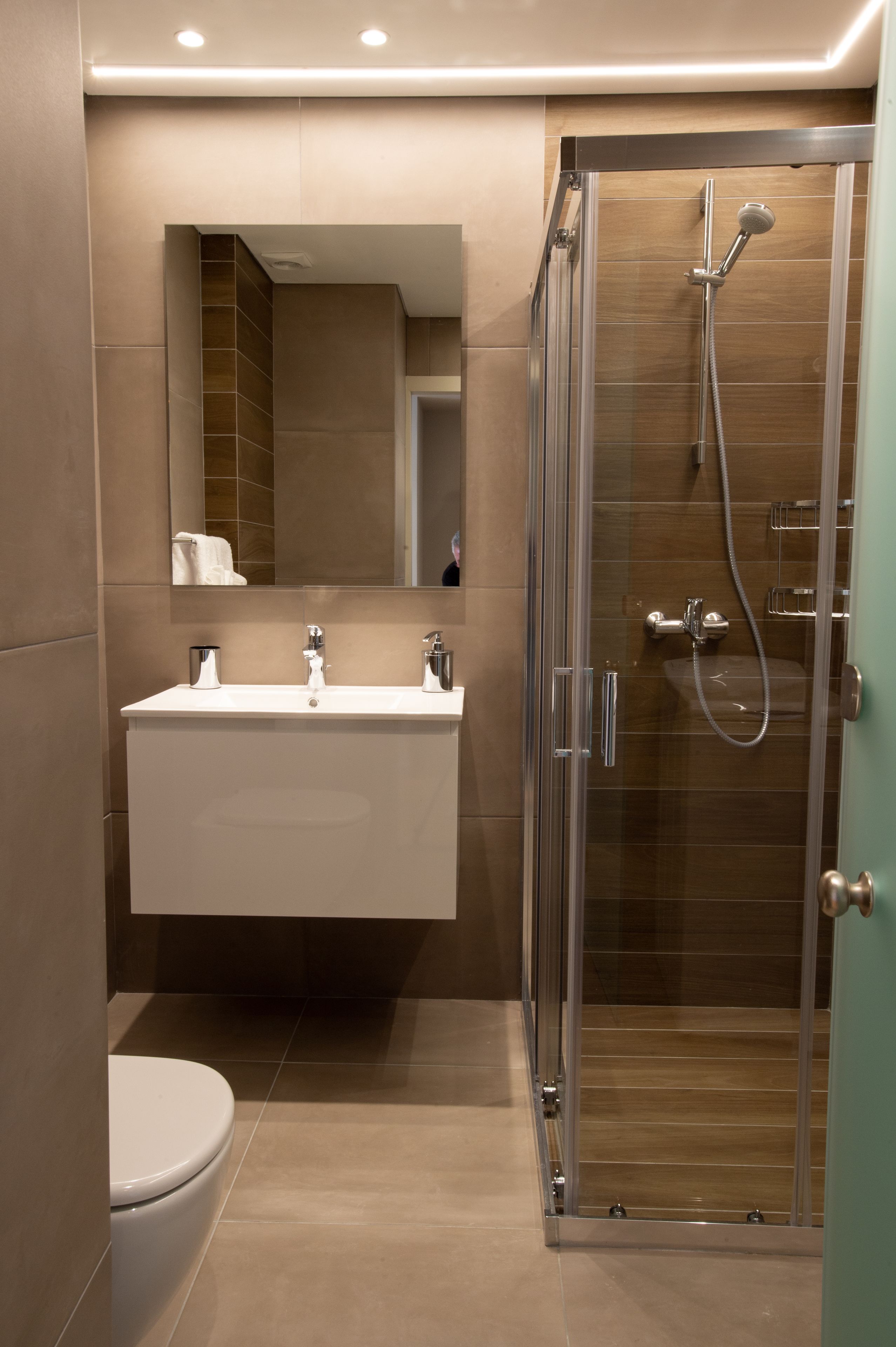 A modern bathroom with a glass shower enclosure, a white sink, and a toilet.