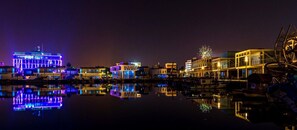 A waterfront area with illuminated buildings and boats. - Blue Home (Limassol)