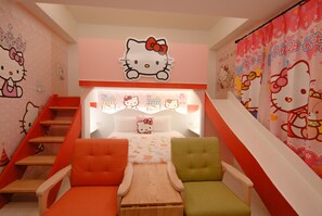 Un dormitorio infantil con temática de Hello Kitty, que incluye una cama, dos sillas, una mesita pequeña y una escalera.