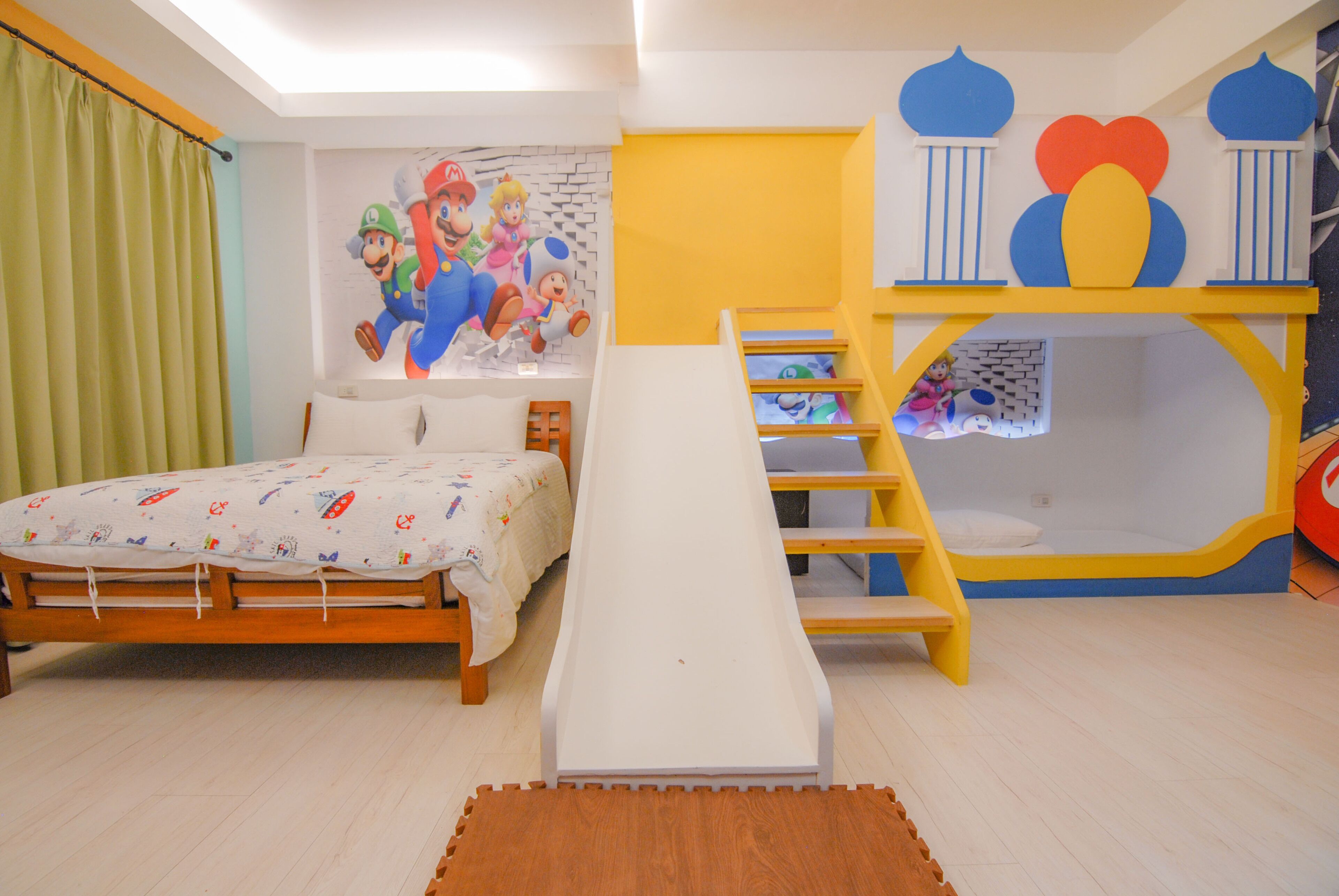 A child's bedroom with a bed, a play area, and a mural of Mario and Luigi.