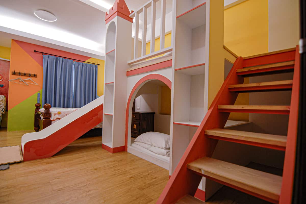 A child's bedroom with a bunk bed, a small desk, and a staircase.