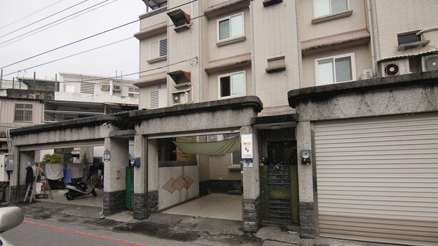 A multi-story building with a garage entrance, a covered area, and a closed garage door. - Staring East B & B (Hualien City)