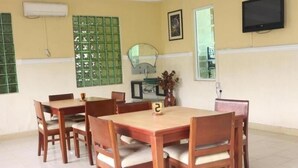 A dining area with wooden tables and chairs, a green decorative wall, a mirror, and a television mounted on the wall. - Hotel Icon Limited (Calabar)
