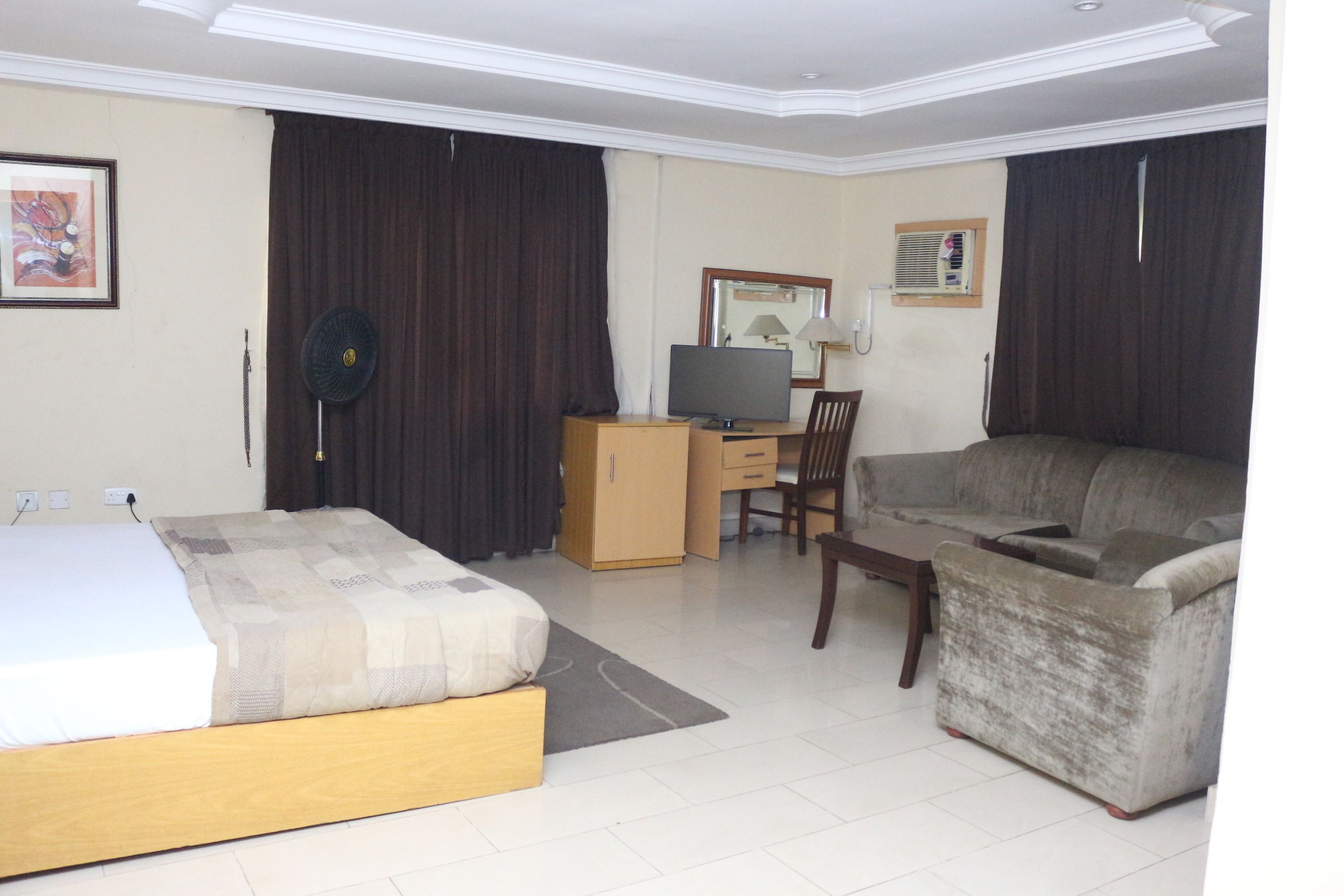 Una habitación de hotel con cama, escritorio con computadora, sofá y una silla.