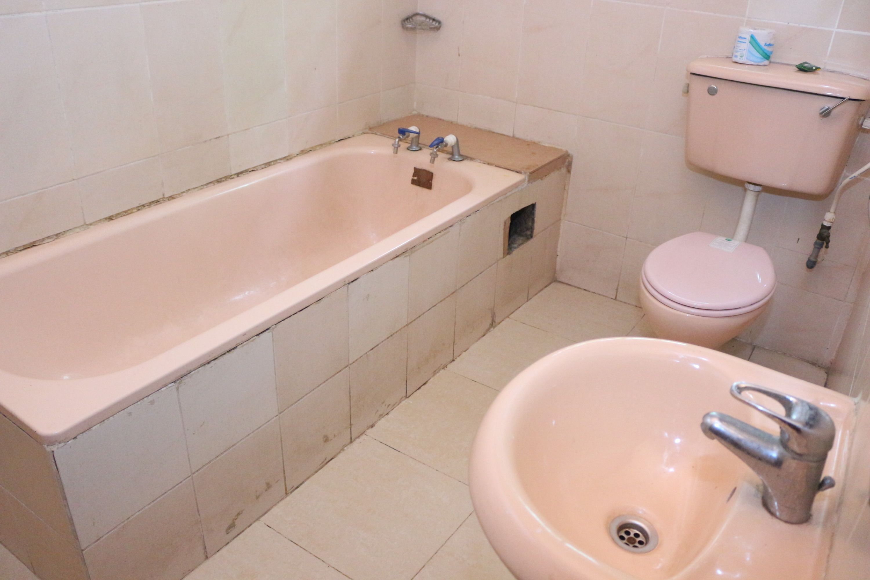 Une salle de bain avec une baignoire, un lavabo, des toilettes et des murs carrelés.