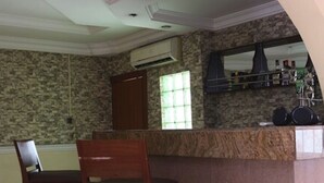 A kitchen with a stone wall, wooden chairs, an air conditioning unit, and a window. - Hotel Icon Limited (Calabar)