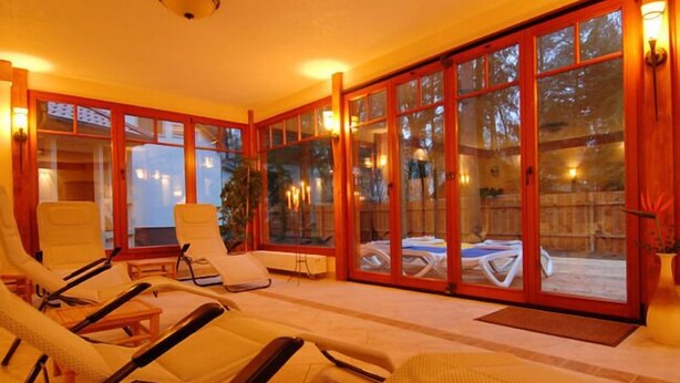 A sunlit room with large glass doors, multiple lounge chairs, and a ceiling fan.