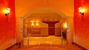 A spa area with a large hot tub, a staircase, and two wall-mounted lights.