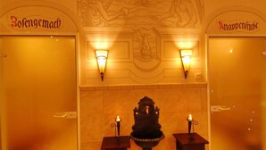 A hotel lobby with two doors labeled "Zofengemach" and "Snappenhube," each with a wall-mounted light fixture.