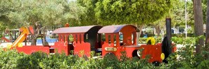 Explore a miniature train set amidst lush greenery in a family-friendly park setting.