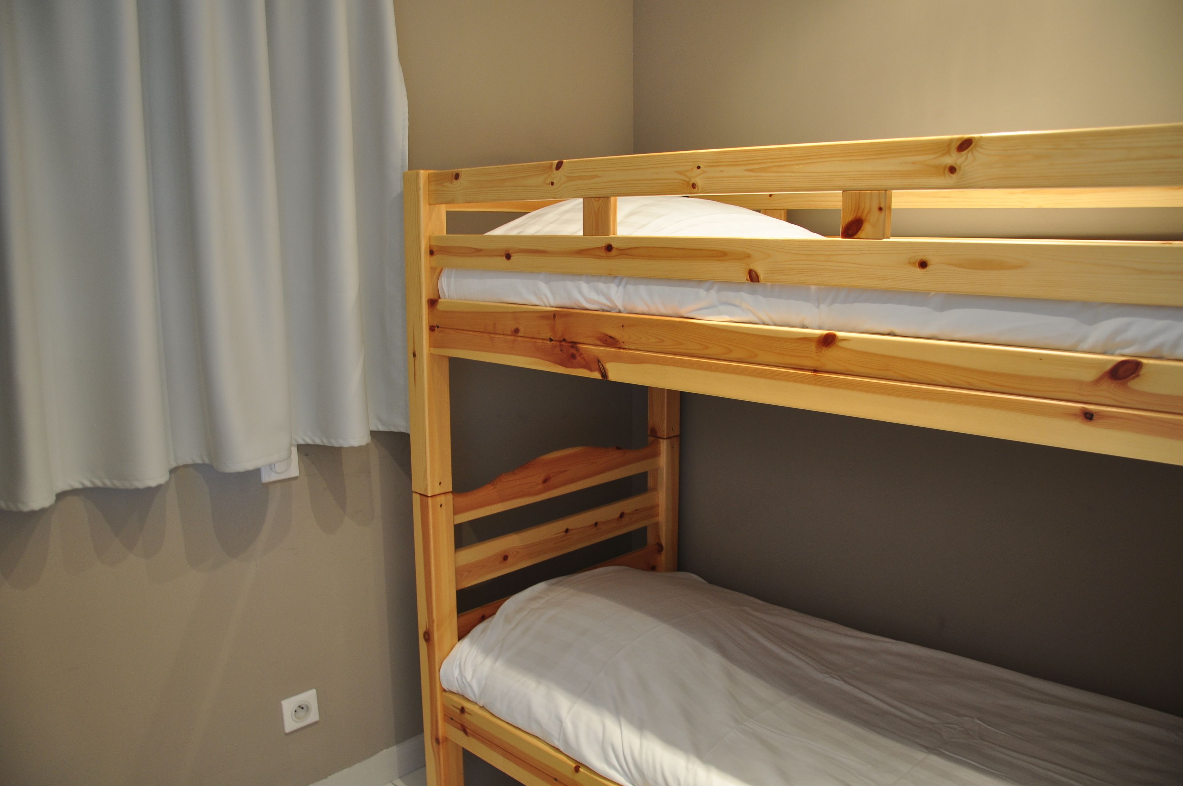 Una cama litera con estructura de madera y ropa de cama blanca.