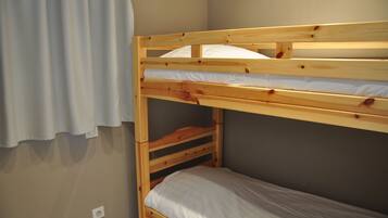 Una cama litera con estructura de madera y ropa de cama blanca.