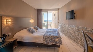 Een moderne hotelkamer met een groot bed, een flatscreen televisie aan de muur en een balkon met uitzicht.
