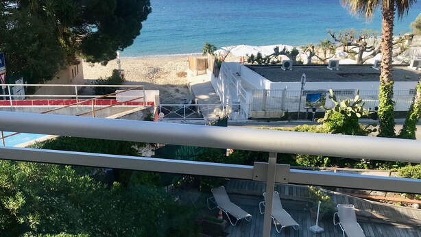 Een ontbijfwagen met gebak, sap en Danone yoghurt op een balkon met uitzicht op een strand.