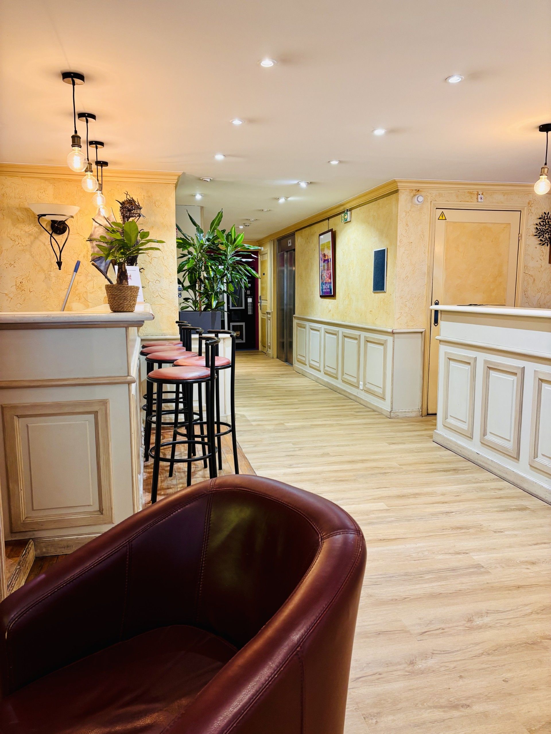 Un vestíbulo de hotel con zona de bar, asientos y una escalera que conduce a otras plantas.