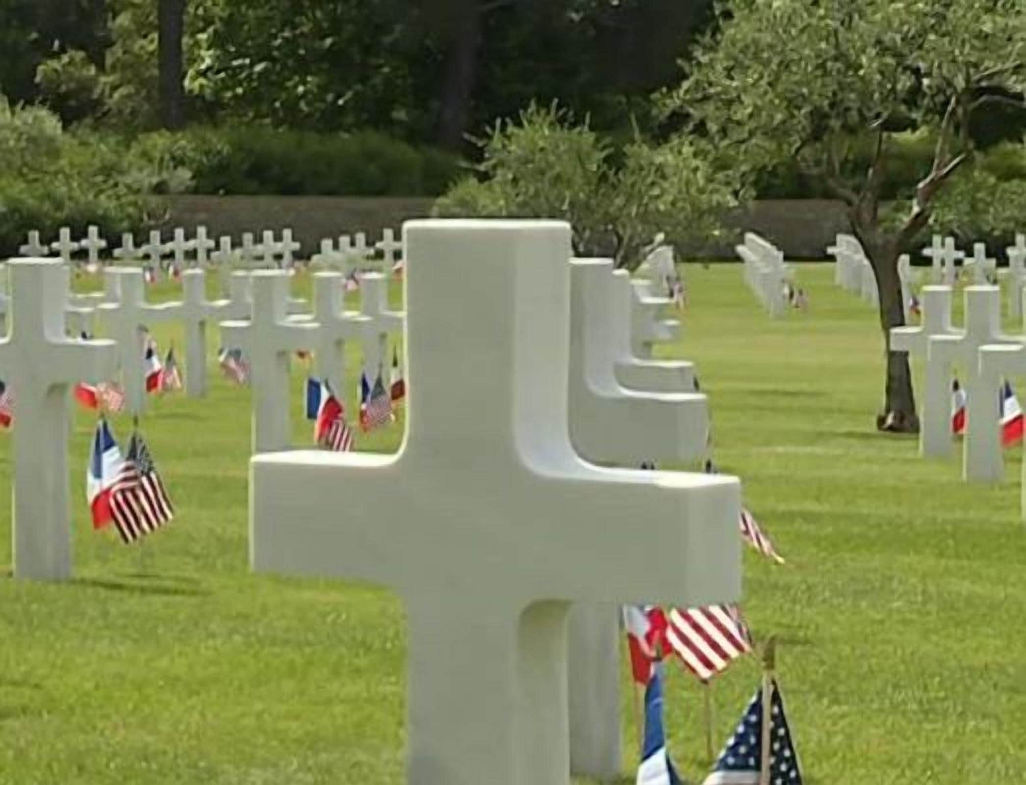 Un cementerio con numerosas cruces blancas y banderas estadounidenses.